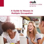 Young adults sitting in a kitchen laughing - Thought Leadership article - A Guide to Houses in Multiple Occupation