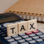 Tax written on a wooden cube on calculator
